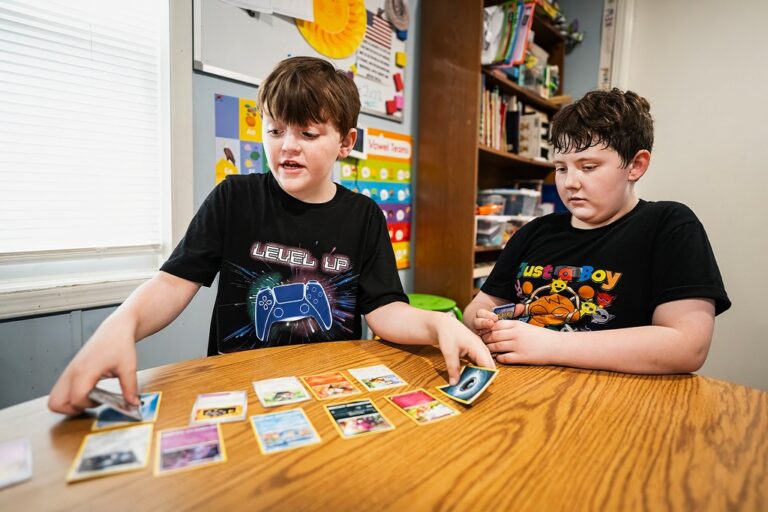 Two young trainers playing a casual Pokémon card match at a table
